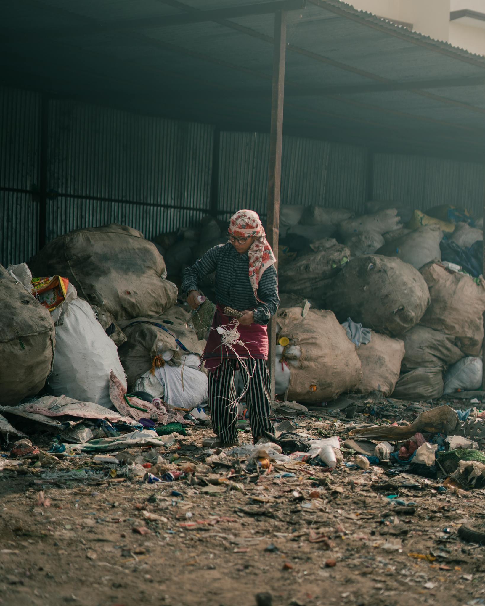 Female worker sorting trash at a recycling facility, promoting waste management.