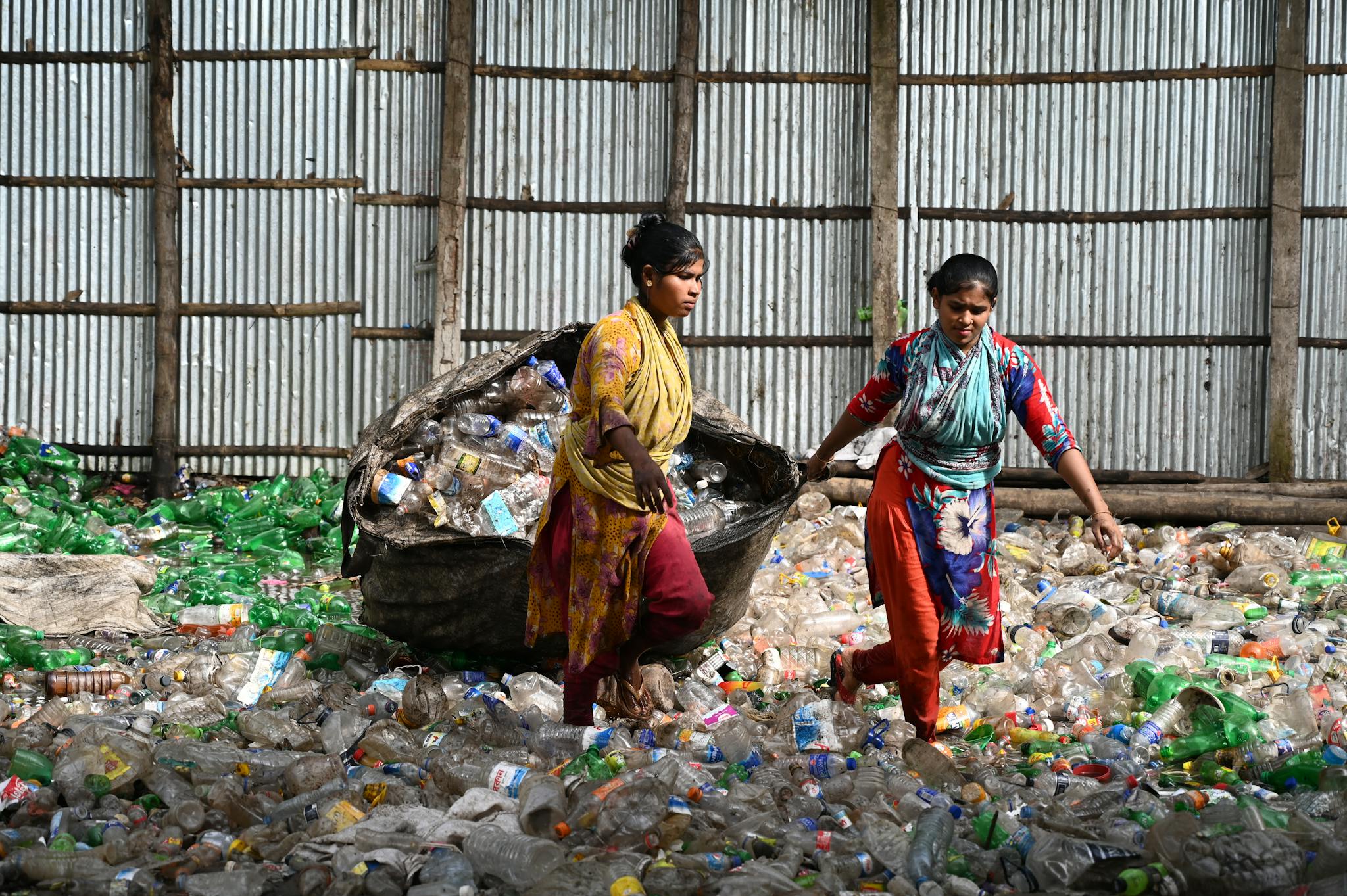 Two women sorting plastic bottles at a recycling facility in Chittagong, Bangladesh.